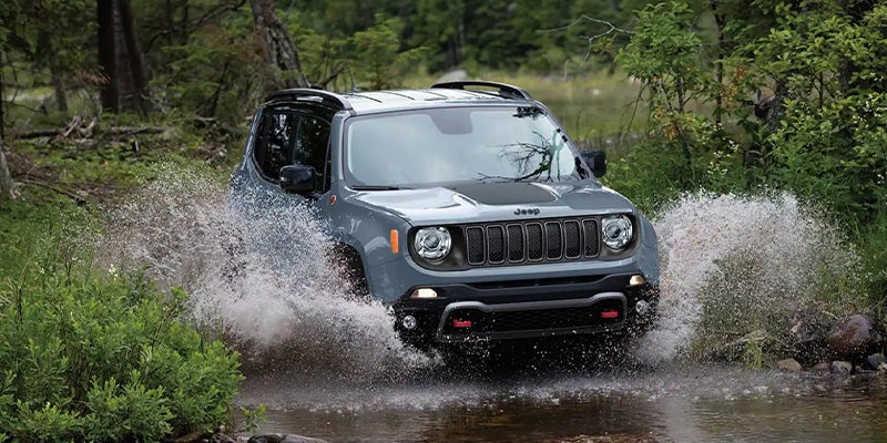 Gray Jeep Renegade SUV driving through a deep water puddle