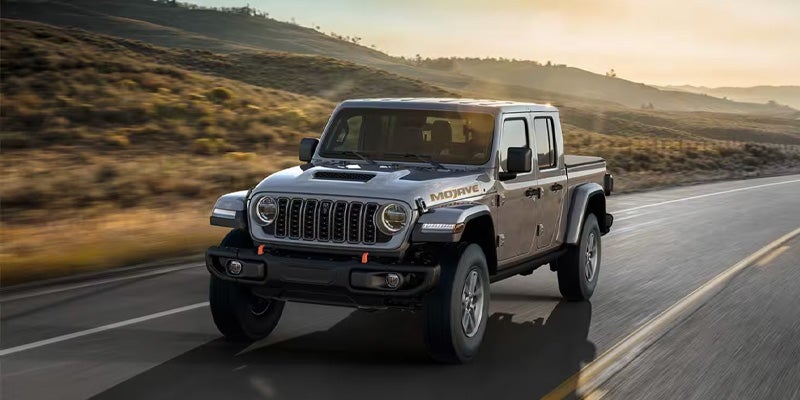 Gray Jeep Gladiator Mojave truck driving on a desert road.