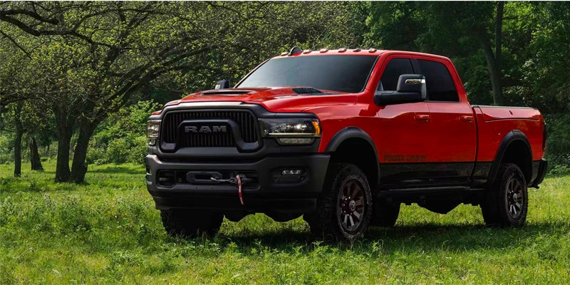 Red Ram Power Wagon pickup truck parked in a grassy, wooded area